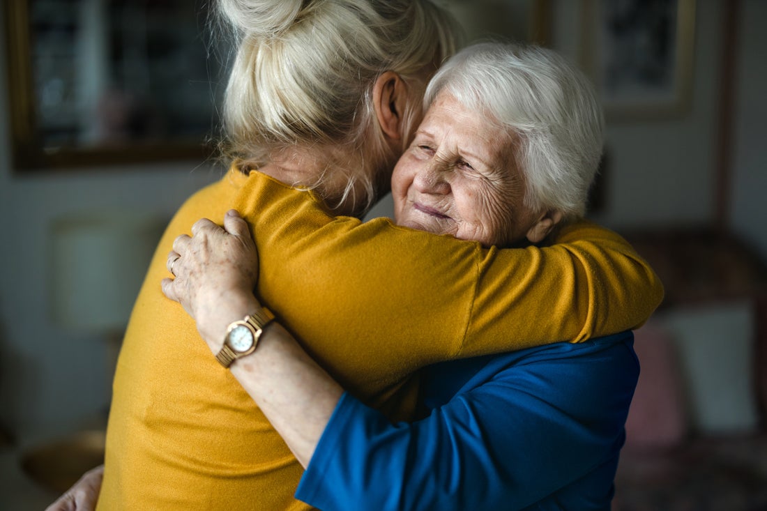 A woman smiles as she receives a hug.