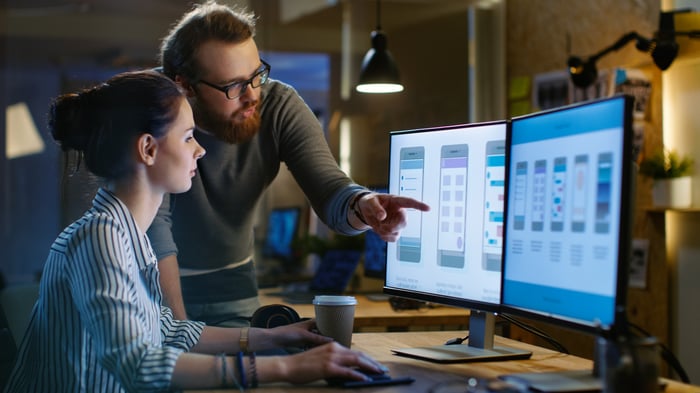 Two user interface designers work together at a workstation.