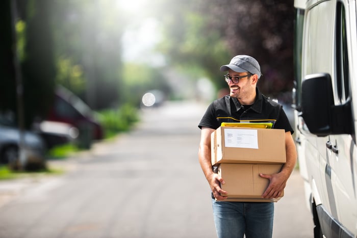 Delivery person carrying packages on a street.