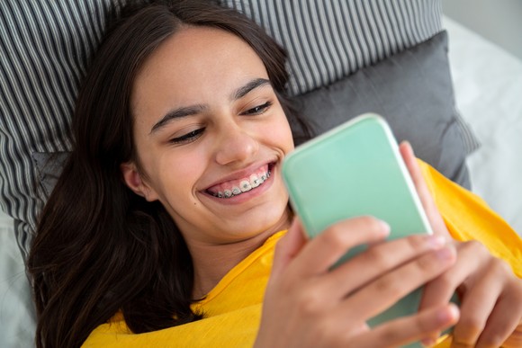 A person smiling at a smartphone.