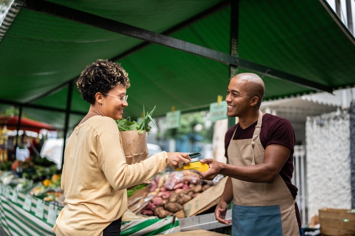 A person makes a payment from their phone in an outdoor market.