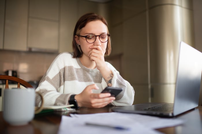 Thoughtful stock trader gazes at smartphone. 