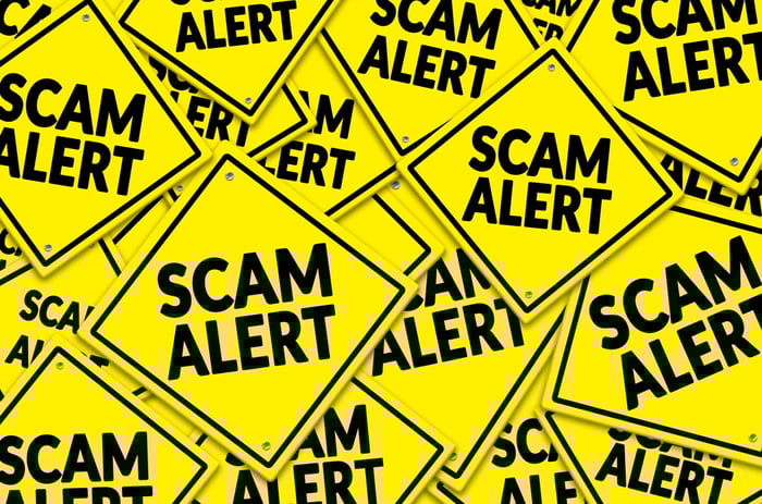 Dozens of bright yellow "Scam Alert" signs stacked on top of each other. 