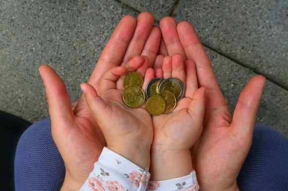 Adult and child hands holding coins.