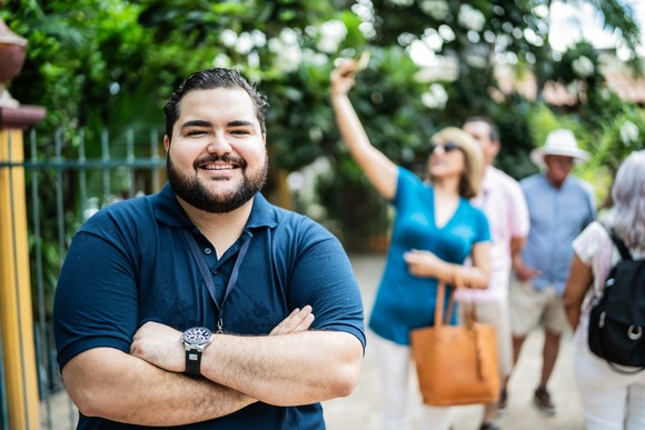 Person in a blue shirt is smiling, with arms crossed.