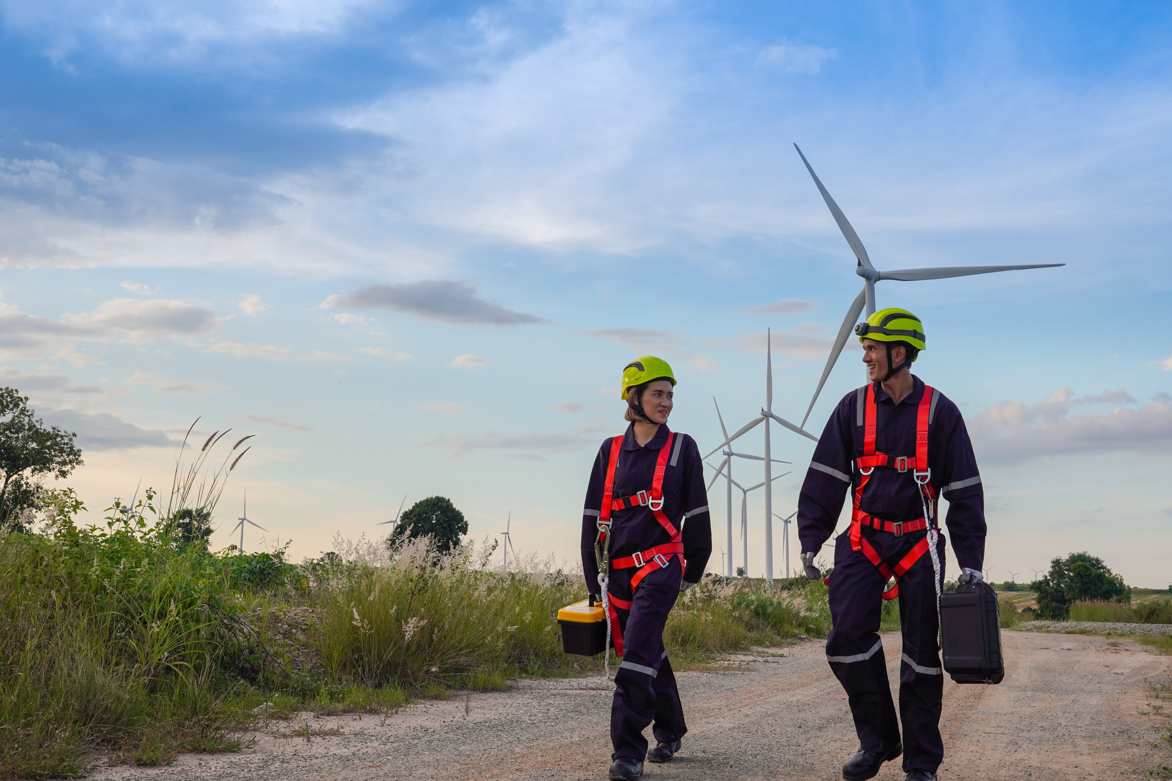 2 workers in front of a set of wind turbines