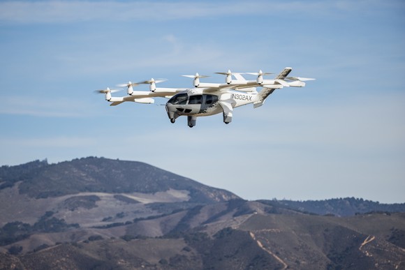 A white Archer Aviation electric vertical takeoff and landing (eVTOL) in flight under a clear blue sky. 