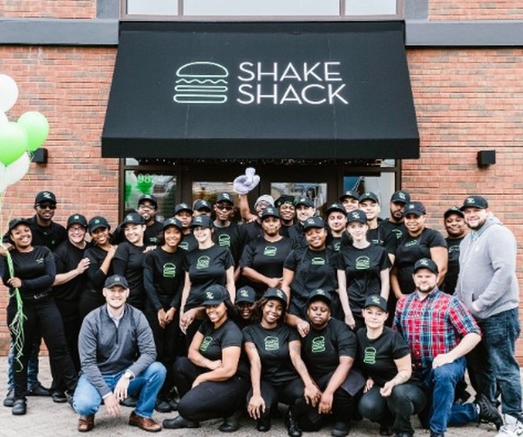 Some Shake Shack employees pose outside a store.