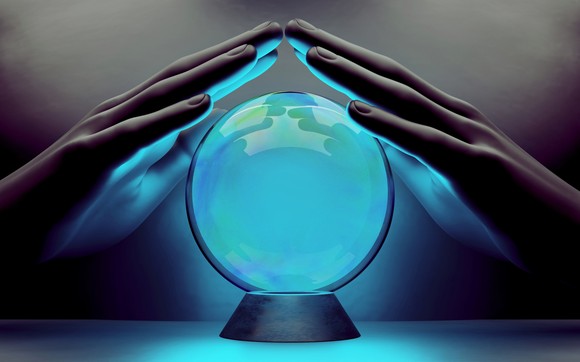 Two hands over a blue, glowing crystal ball.