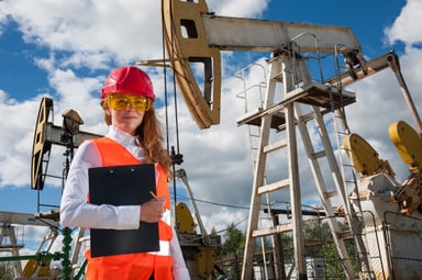 oil worker with clipboard in front of pumpjack.