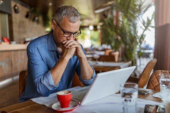 A person looks at a laptop in a cafe.