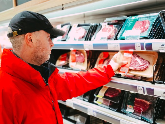 Someone picking out meat in a store.
