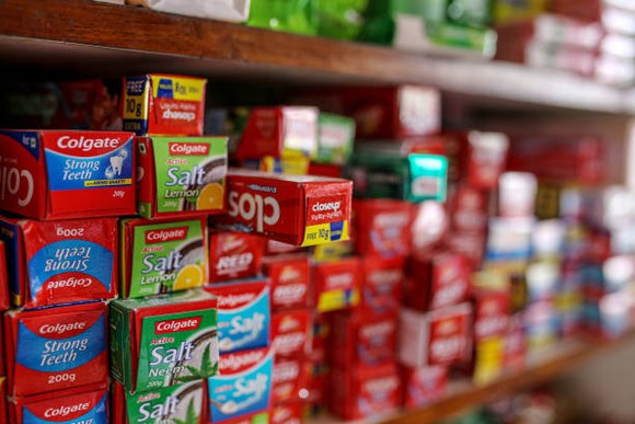 Boxes of Colgate-Palmolive toothpaste line a store shelf.