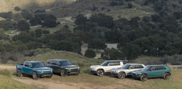 All Rivian electric truck and SUV models parked on a hill.