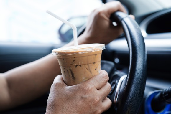 A person holding a cold beverage while driving.