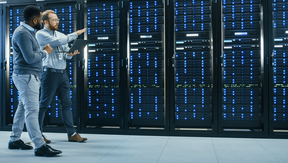 Two engineers walking along a row of servers in a data center.