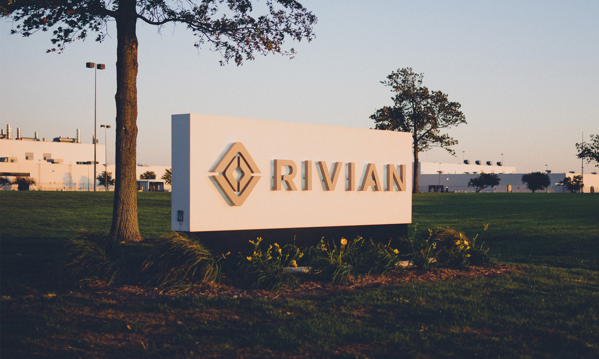 building with rivian logo sign on front lawn.