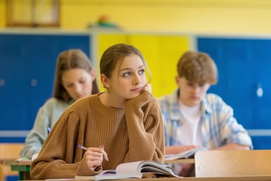students sit at desks in classroom.