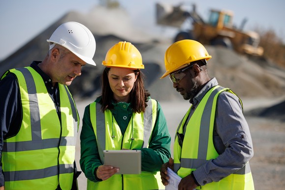 Three construction engineers review plans on the job site.