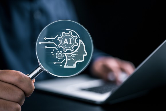A person holds a magnifying glass displaying an AI icon.