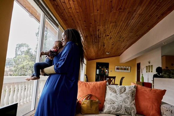 Person holding baby and looking out window.