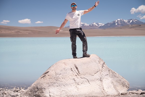 Man stands on top of mound of lithium sand. 