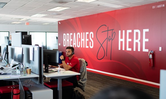 Someone sitting in a CrowdStrike office at a computer.