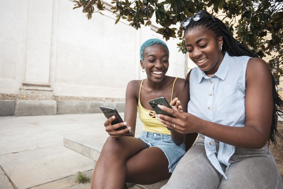 Two people smile while playing on social media apps.