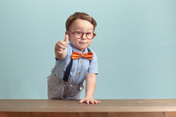 boy wearing bow tie gives thumbs up.