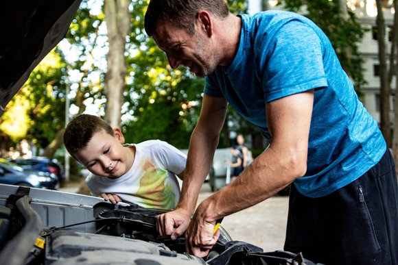 A man and his son work on his car.