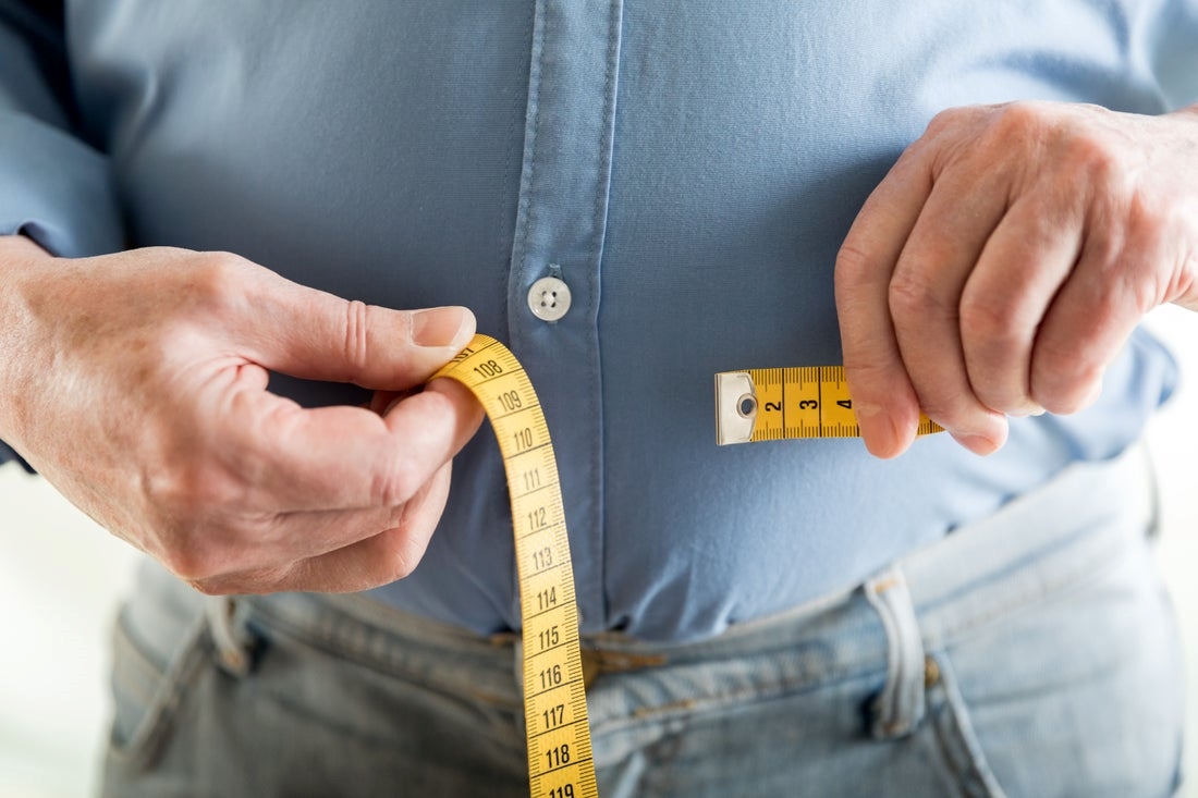 Person using a measuring tape around their waist.