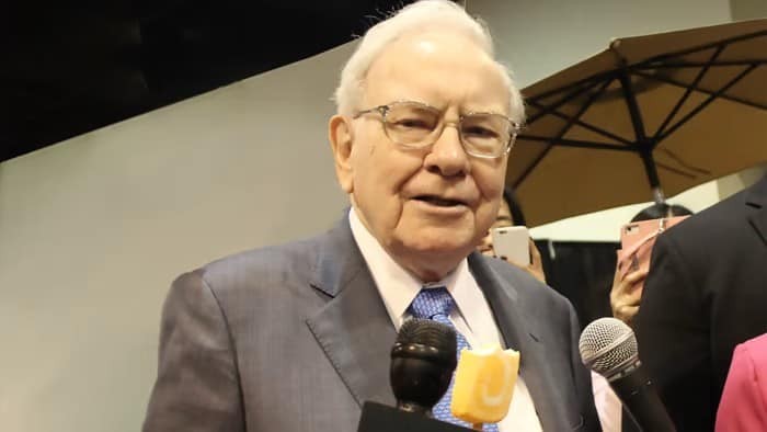 Warren Buffett stands before a microphone.