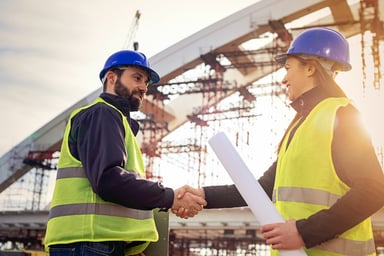 People shaking hands at a construction site.