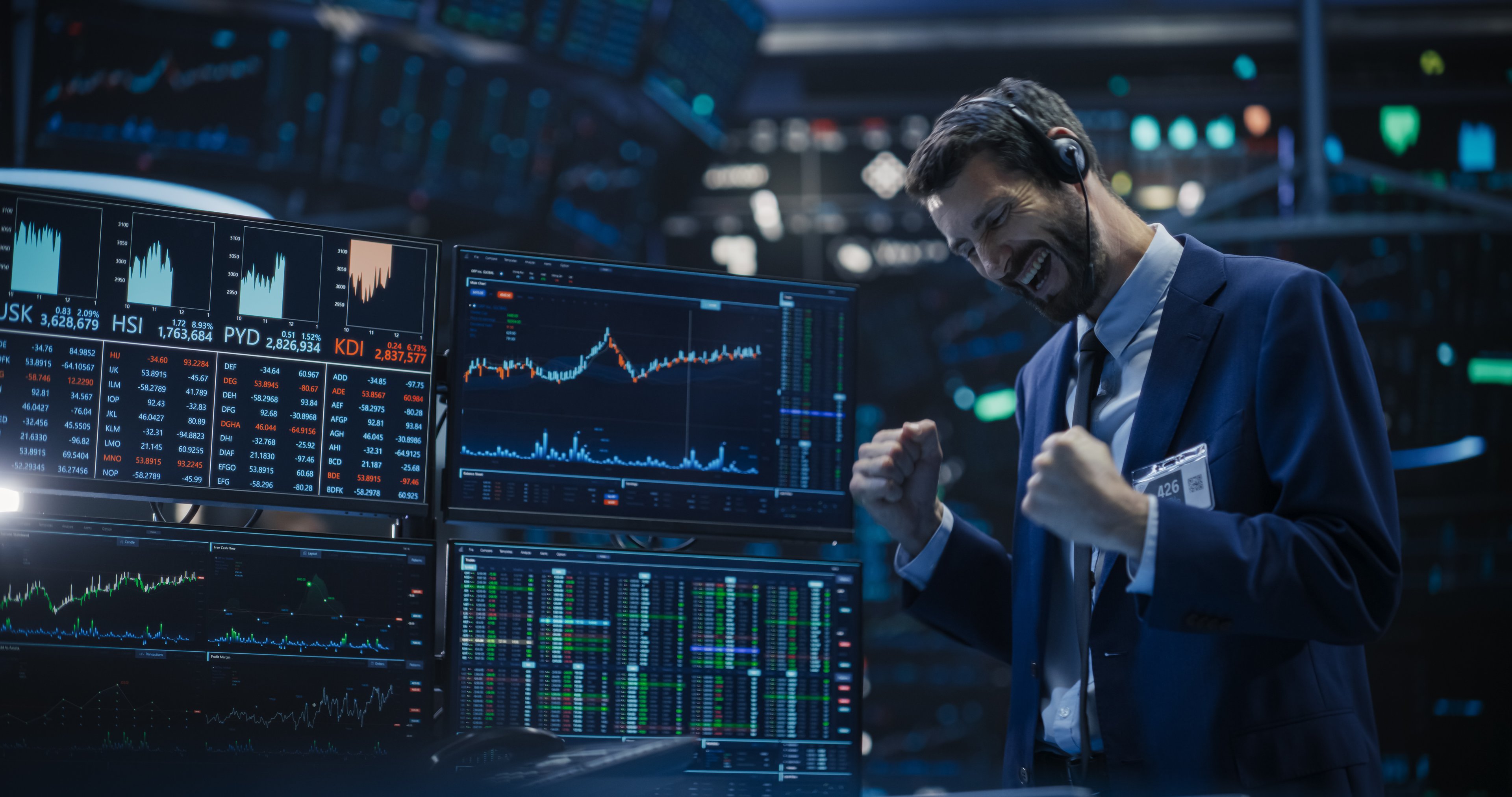 A trade cheers while looking at multiple trading screens.