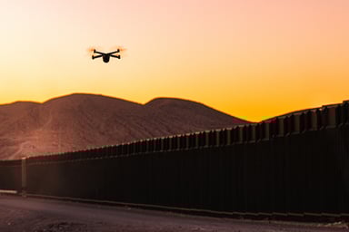 Quadcopter drone patrolling a border wall.