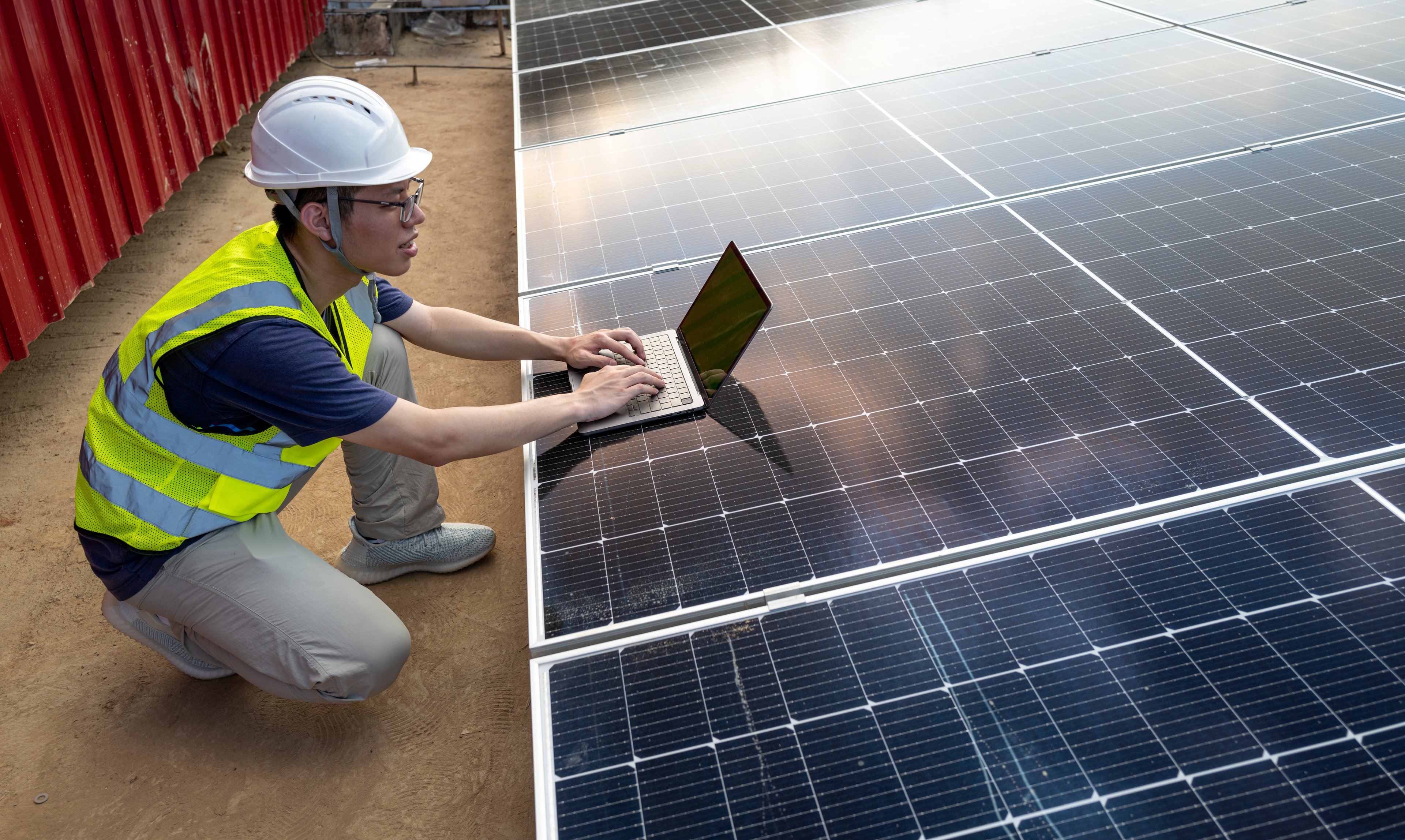 Person using a laptop on top of a solar panel