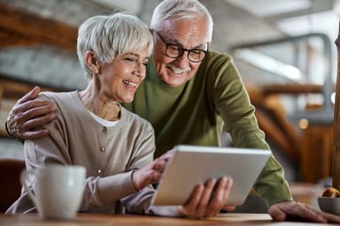 Two investors smile as they look at a tablet. 