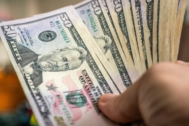 A hand holding $50 bills.