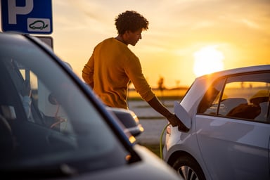 driver charges an electric vehicle at dusk.
