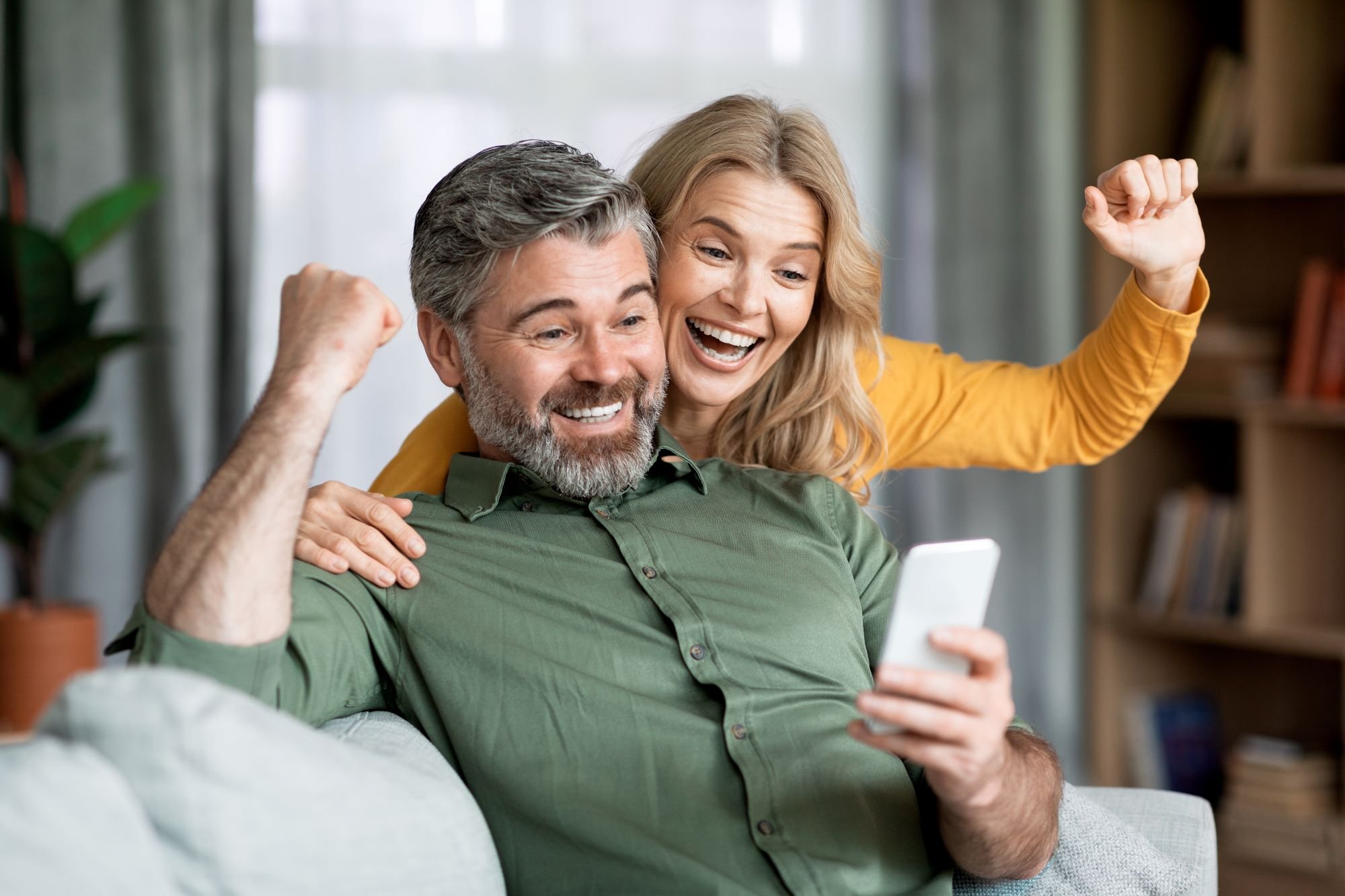 An excited couple looking at a cell phone.