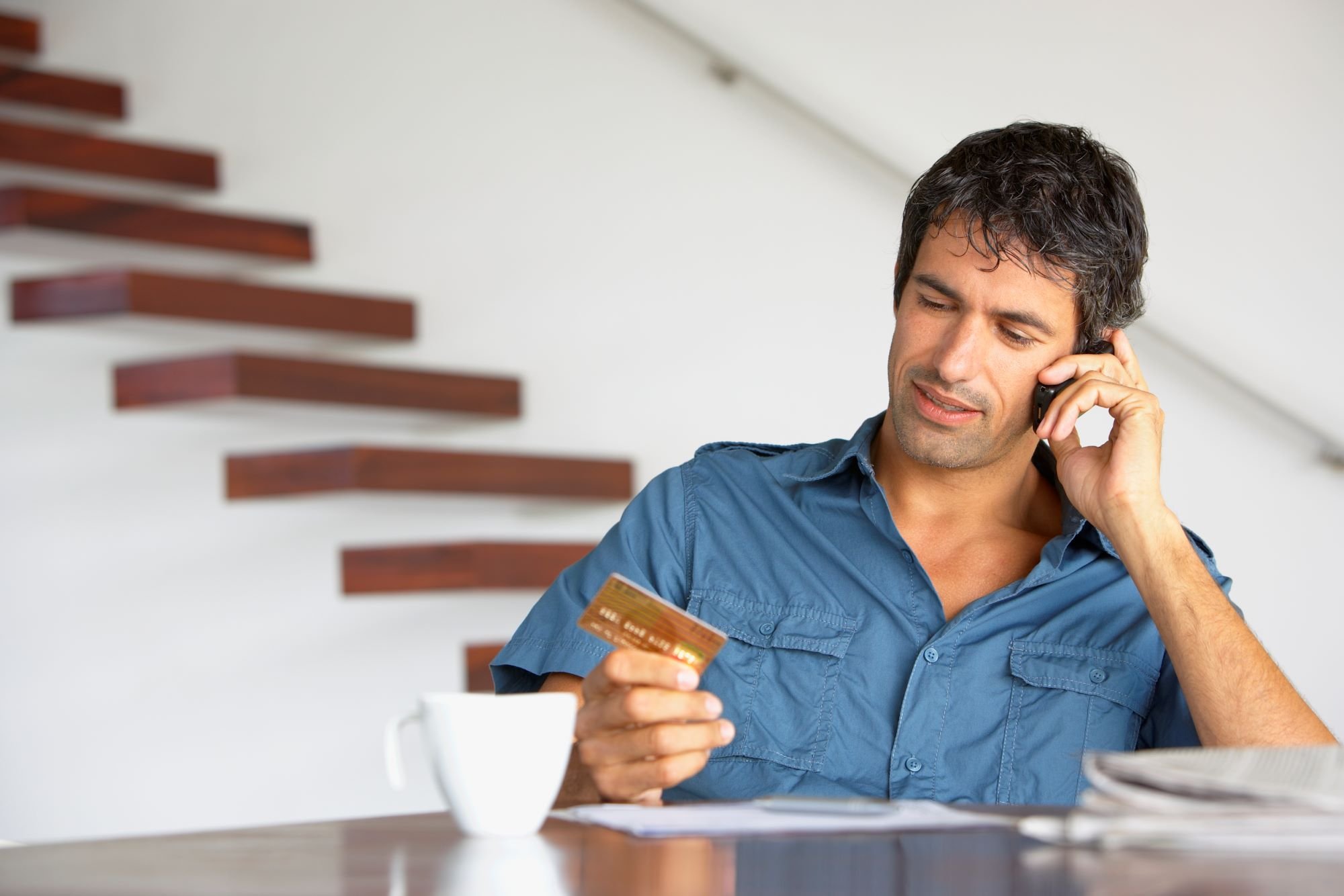 Person on the phone while holding a credit card.
