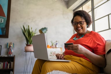 Person holding a credit card and a laptop