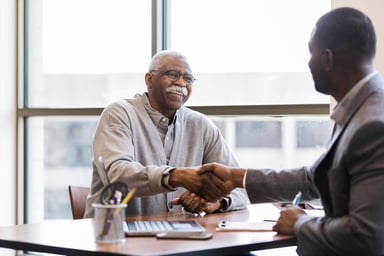 Two people shaking hands at a meeting.