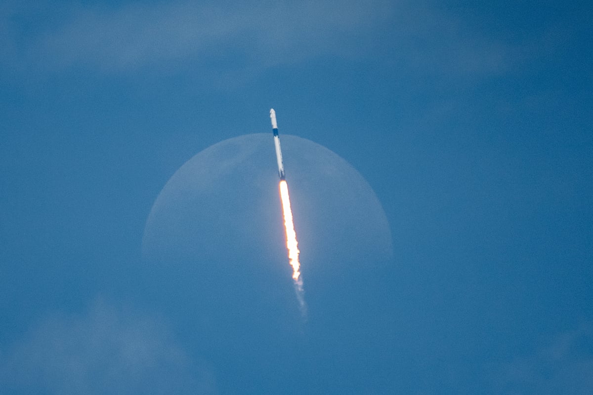 Rocket launching into space with moon in background.