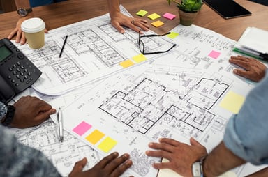 Workers spread out blueprints on a table