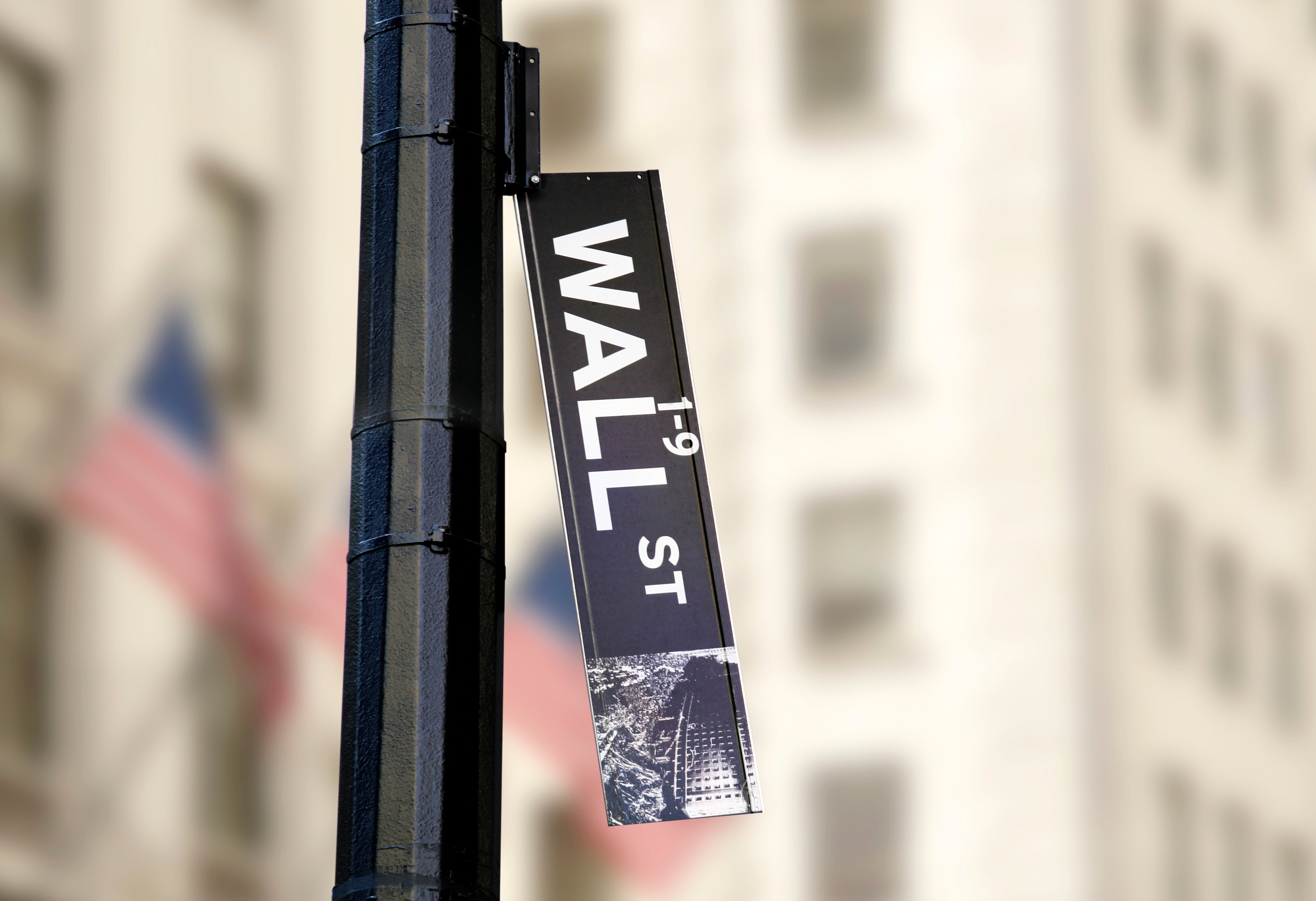 A Wall Street sign falling off its signpost