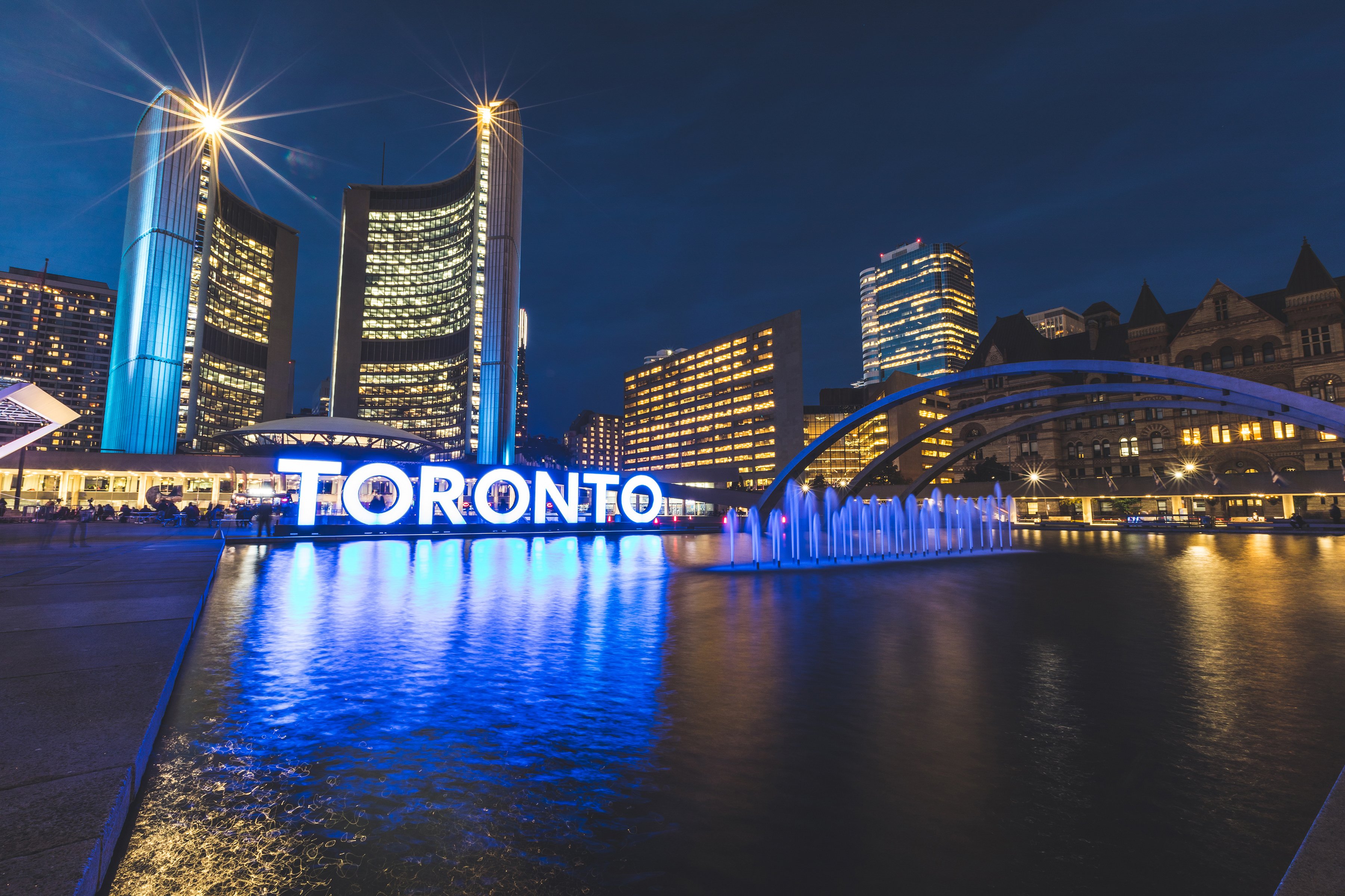 Image of the Toronto skyline at night, in view of the TORONTO sign.