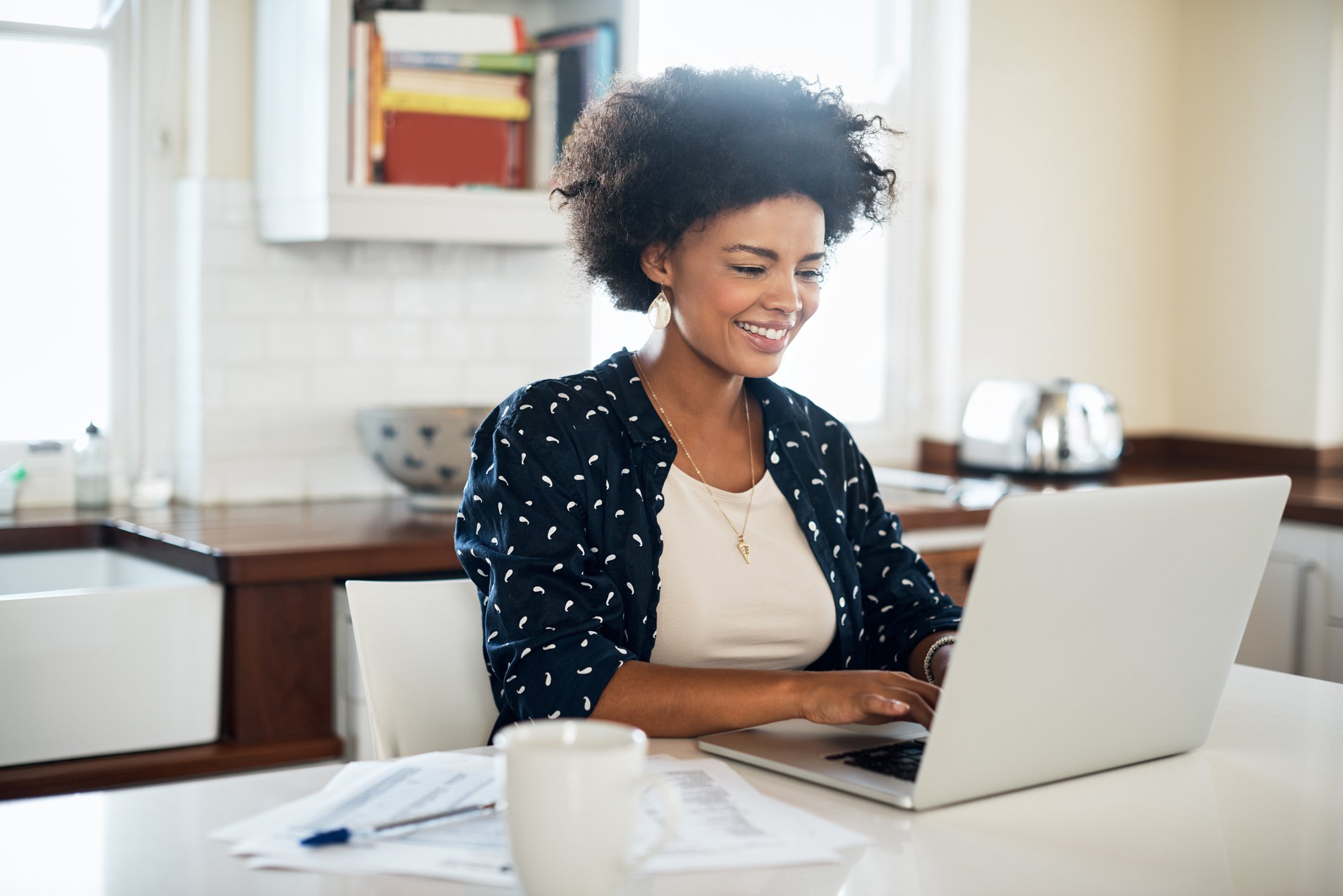 Person smiling while using laptop in a kitchen