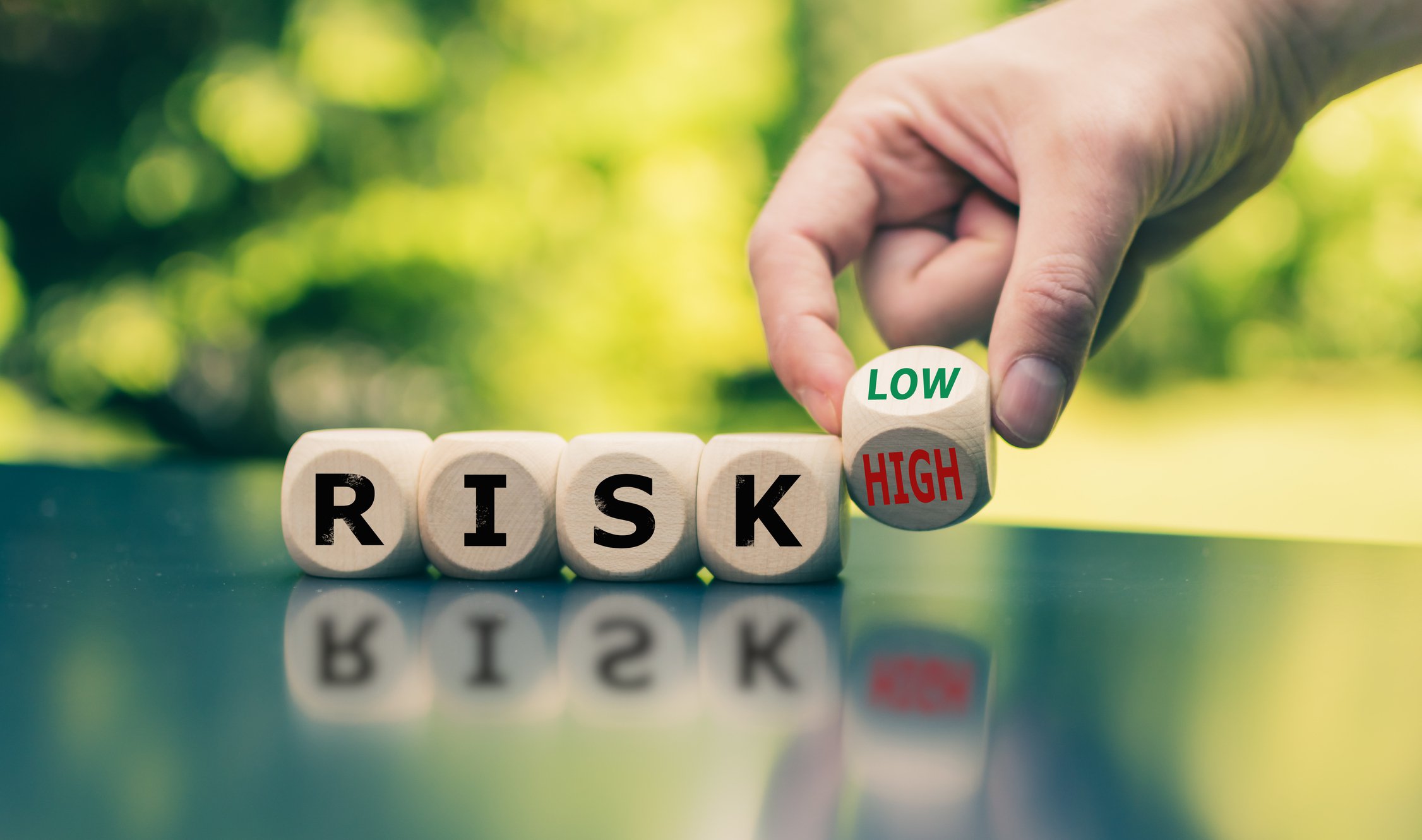 Blocks spelling out the word RISK with the final block being turned from Low to High.