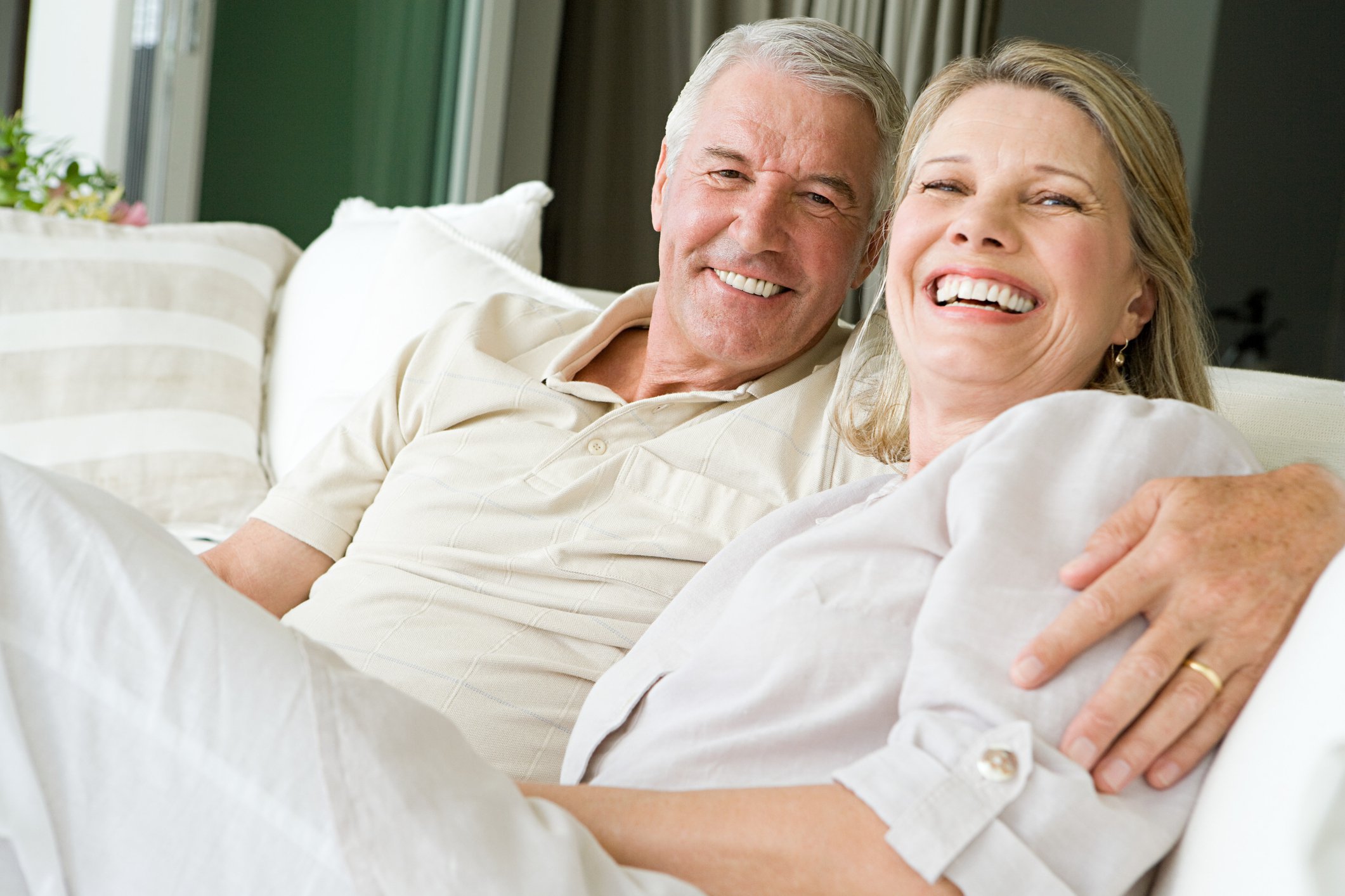 Older couple together smiling on a couch.